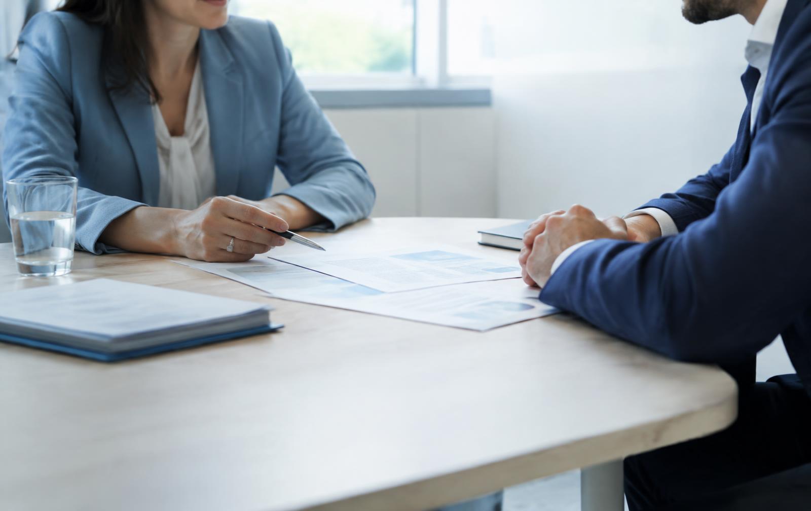 Dos personas revisando documentos en una mesa durante una reunión de mediación